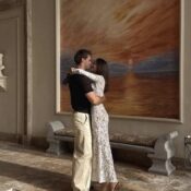 A stylish couple embracing warmly in a contemporary art gallery, sharing a tender and intimate moment while enjoying the art around them.